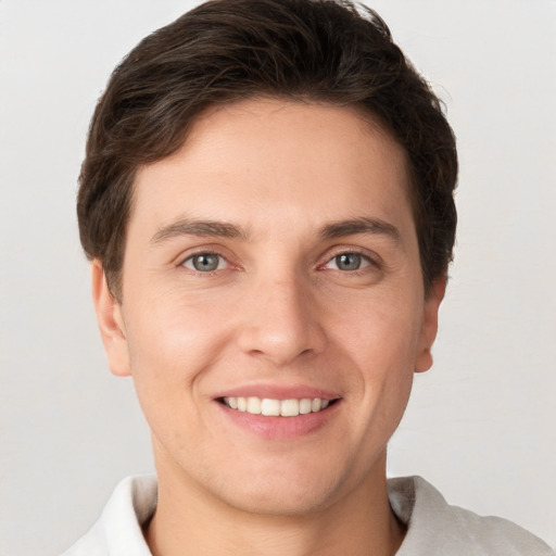 Joyful white young-adult male with short  brown hair and grey eyes