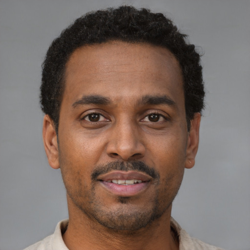 Joyful black young-adult male with short  brown hair and brown eyes