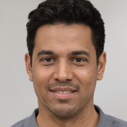 Joyful latino young-adult male with short  black hair and brown eyes