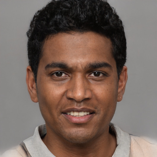 Joyful black young-adult male with short  black hair and brown eyes