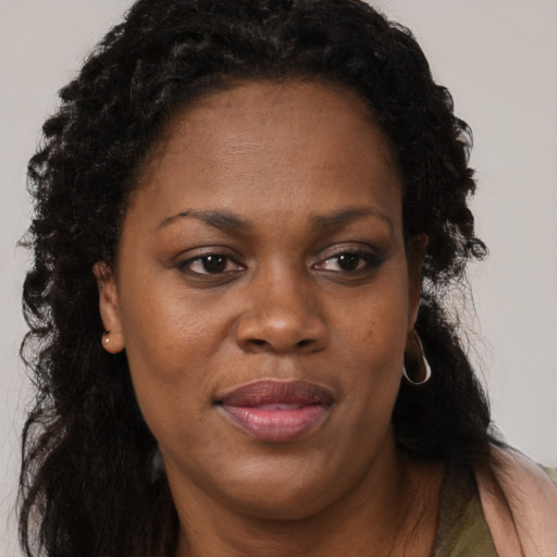 Joyful black adult female with long  brown hair and brown eyes