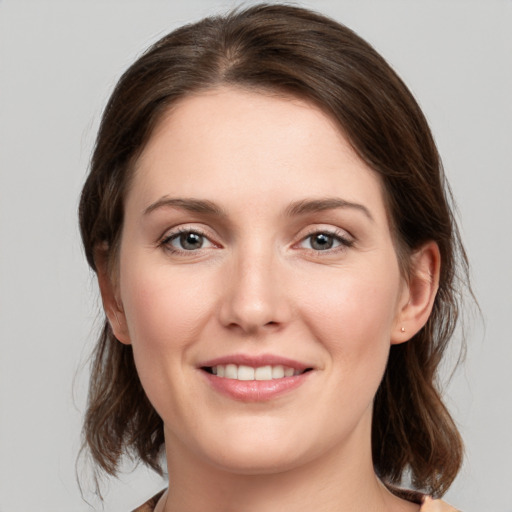 Joyful white young-adult female with medium  brown hair and grey eyes