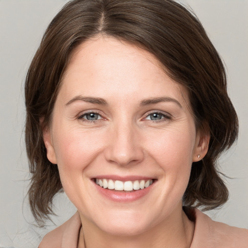 Joyful white young-adult female with medium  brown hair and grey eyes