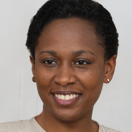 Joyful black young-adult female with short  black hair and brown eyes