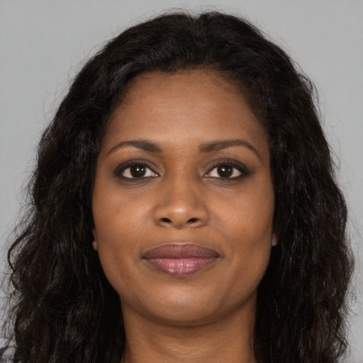 Joyful black young-adult female with long  brown hair and brown eyes