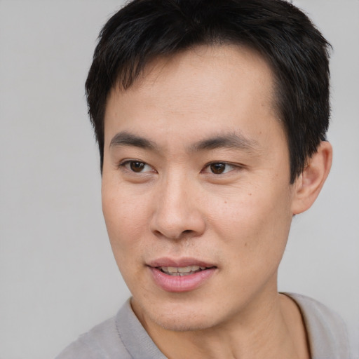 Joyful asian young-adult male with short  brown hair and brown eyes