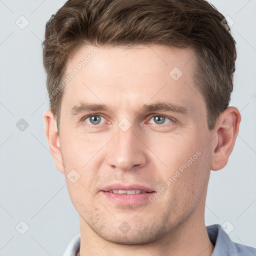 Joyful white young-adult male with short  brown hair and grey eyes