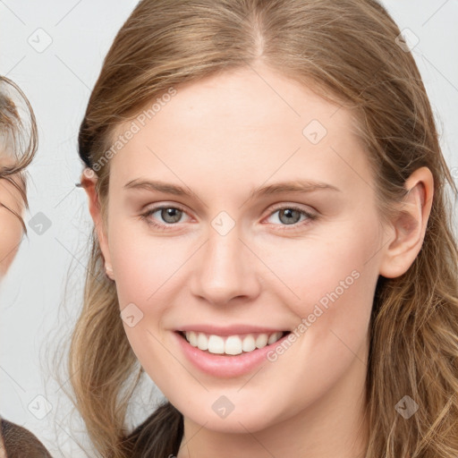 Joyful white young-adult female with long  brown hair and blue eyes