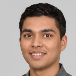 Joyful latino young-adult male with short  black hair and brown eyes