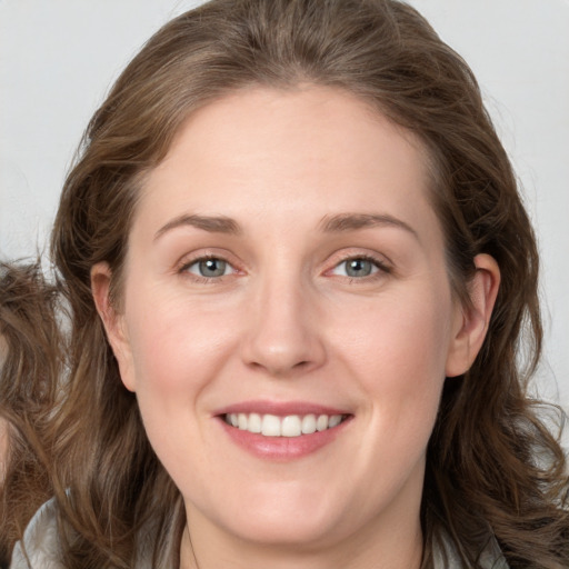 Joyful white young-adult female with long  brown hair and blue eyes