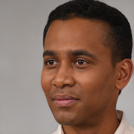 Joyful black young-adult male with short  brown hair and brown eyes