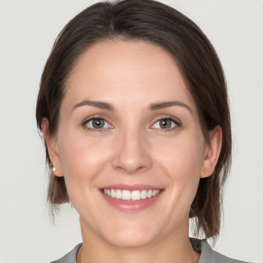 Joyful white young-adult female with medium  brown hair and grey eyes