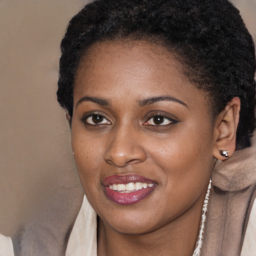 Joyful black young-adult female with short  black hair and brown eyes