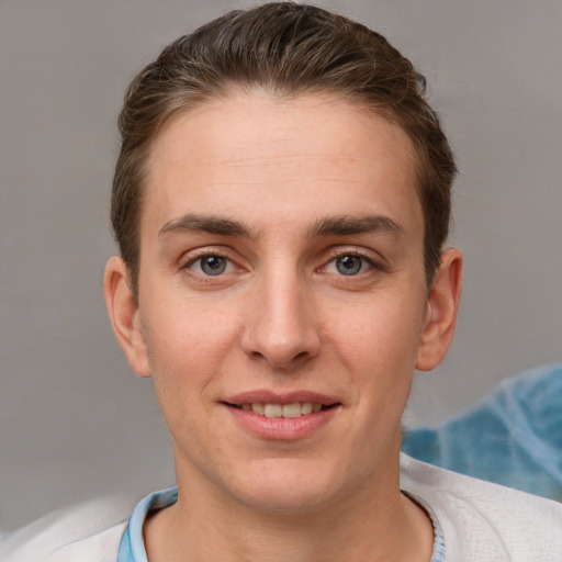 Joyful white young-adult male with short  brown hair and grey eyes