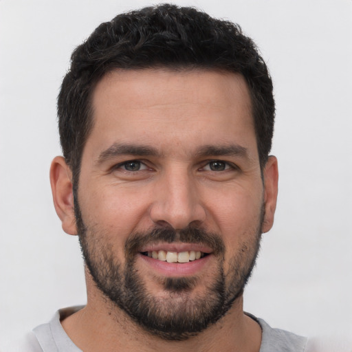 Joyful white young-adult male with short  black hair and brown eyes