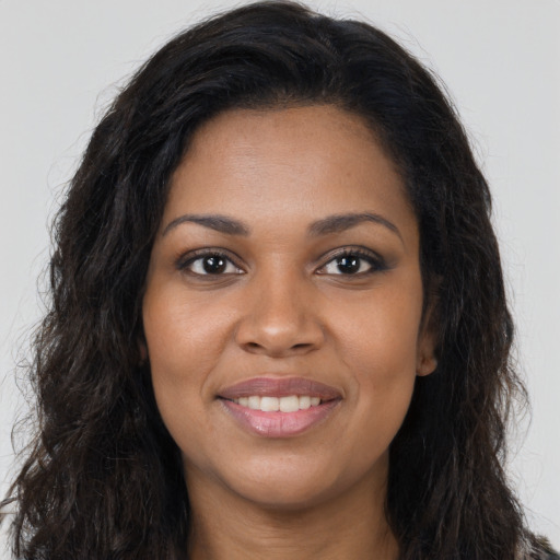 Joyful black young-adult female with long  brown hair and brown eyes
