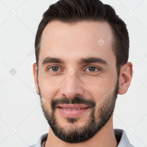 Joyful white young-adult male with short  black hair and brown eyes