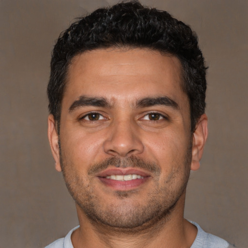 Joyful latino young-adult male with short  black hair and brown eyes
