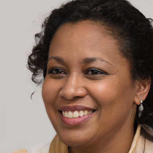 Joyful black young-adult female with long  brown hair and brown eyes