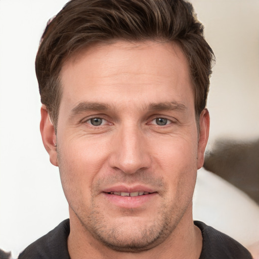 Joyful white young-adult male with short  brown hair and grey eyes