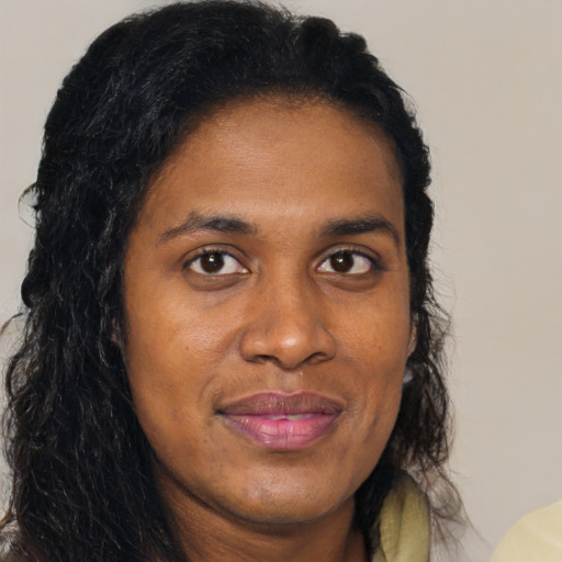 Joyful black young-adult female with long  brown hair and brown eyes