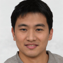 Joyful asian young-adult male with short  brown hair and brown eyes