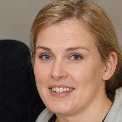 Joyful white adult female with medium  brown hair and blue eyes