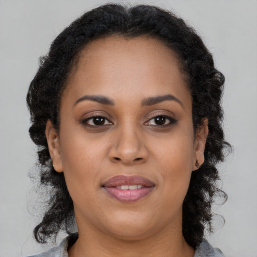 Joyful black young-adult female with long  brown hair and brown eyes
