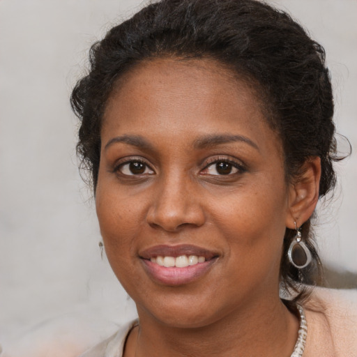 Joyful black young-adult female with long  brown hair and brown eyes
