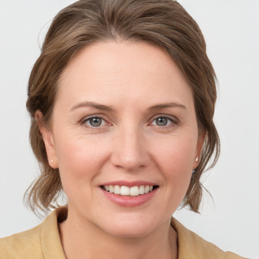 Joyful white young-adult female with medium  brown hair and grey eyes