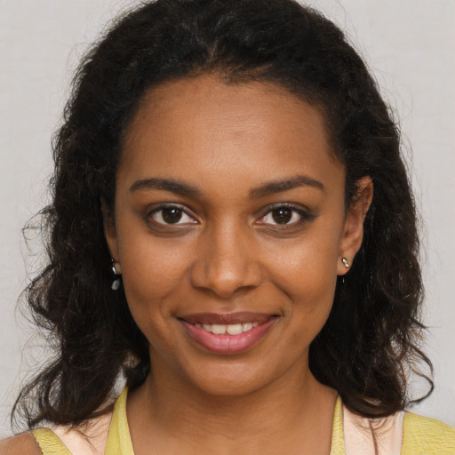 Joyful black young-adult female with long  brown hair and brown eyes