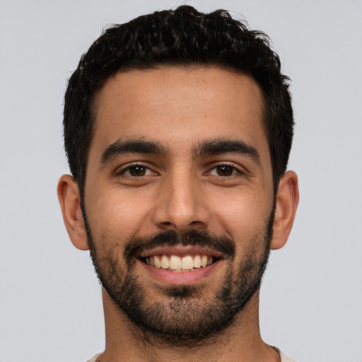 Joyful latino young-adult male with short  black hair and brown eyes