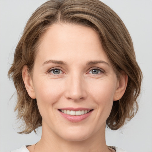 Joyful white young-adult female with medium  brown hair and grey eyes