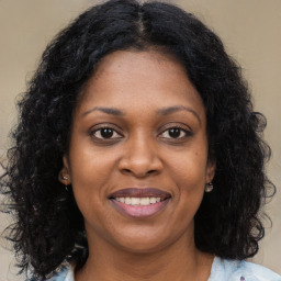 Joyful black young-adult female with long  brown hair and brown eyes