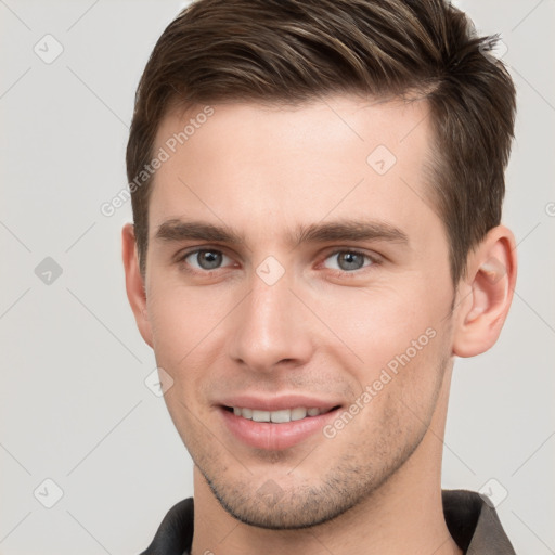 Joyful white young-adult male with short  brown hair and grey eyes