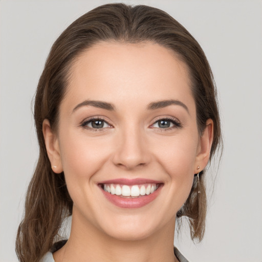 Joyful white young-adult female with medium  brown hair and grey eyes