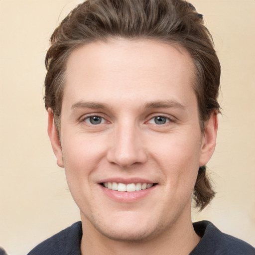 Joyful white young-adult male with short  brown hair and grey eyes