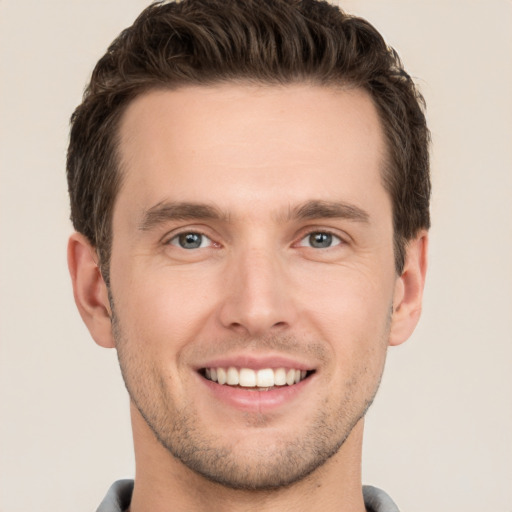 Joyful white young-adult male with short  brown hair and grey eyes