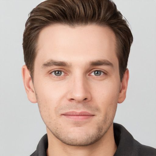 Joyful white young-adult male with short  brown hair and grey eyes