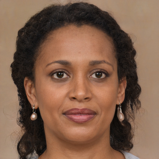 Joyful black adult female with long  brown hair and brown eyes