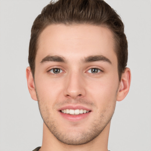 Joyful white young-adult male with short  brown hair and grey eyes