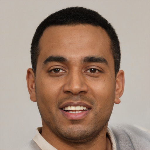 Joyful black young-adult male with short  black hair and brown eyes
