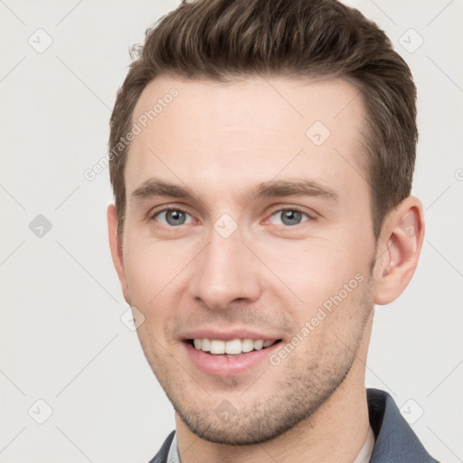 Joyful white young-adult male with short  brown hair and grey eyes