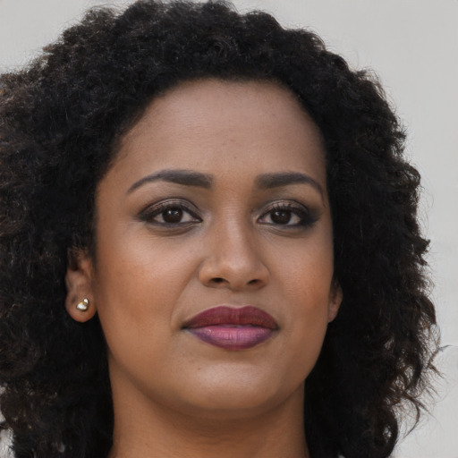 Joyful black young-adult female with long  brown hair and brown eyes