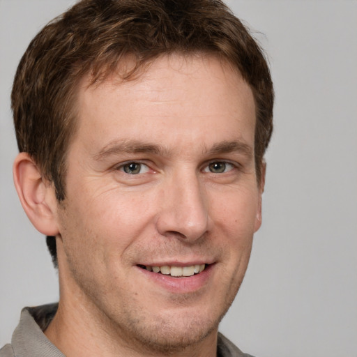 Joyful white adult male with short  brown hair and grey eyes