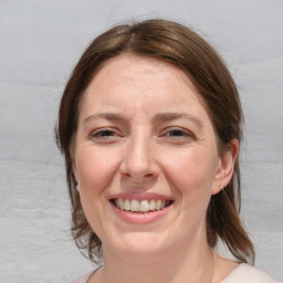 Joyful white adult female with medium  brown hair and blue eyes