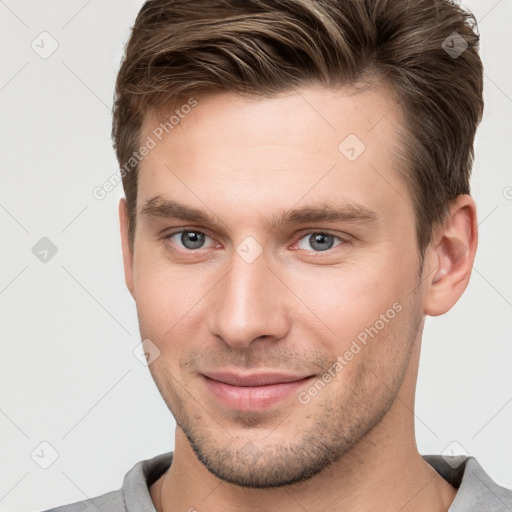 Joyful white young-adult male with short  brown hair and grey eyes