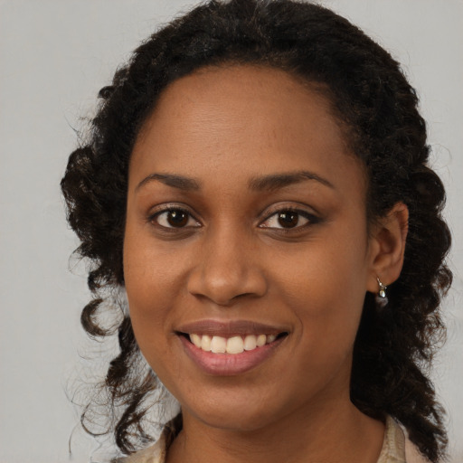 Joyful black young-adult female with long  brown hair and brown eyes