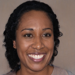 Joyful black adult female with long  brown hair and brown eyes