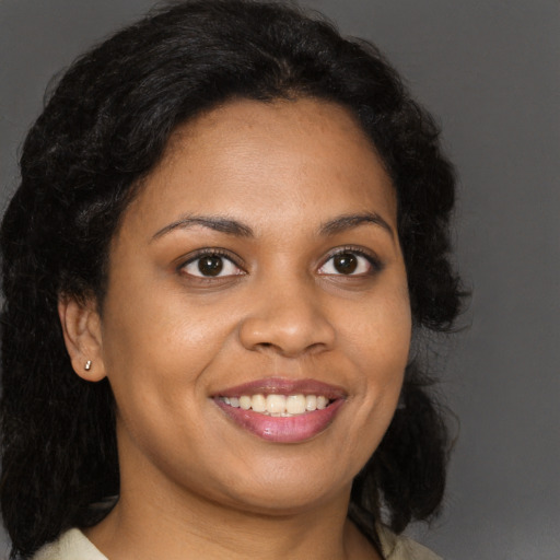 Joyful black young-adult female with long  brown hair and brown eyes